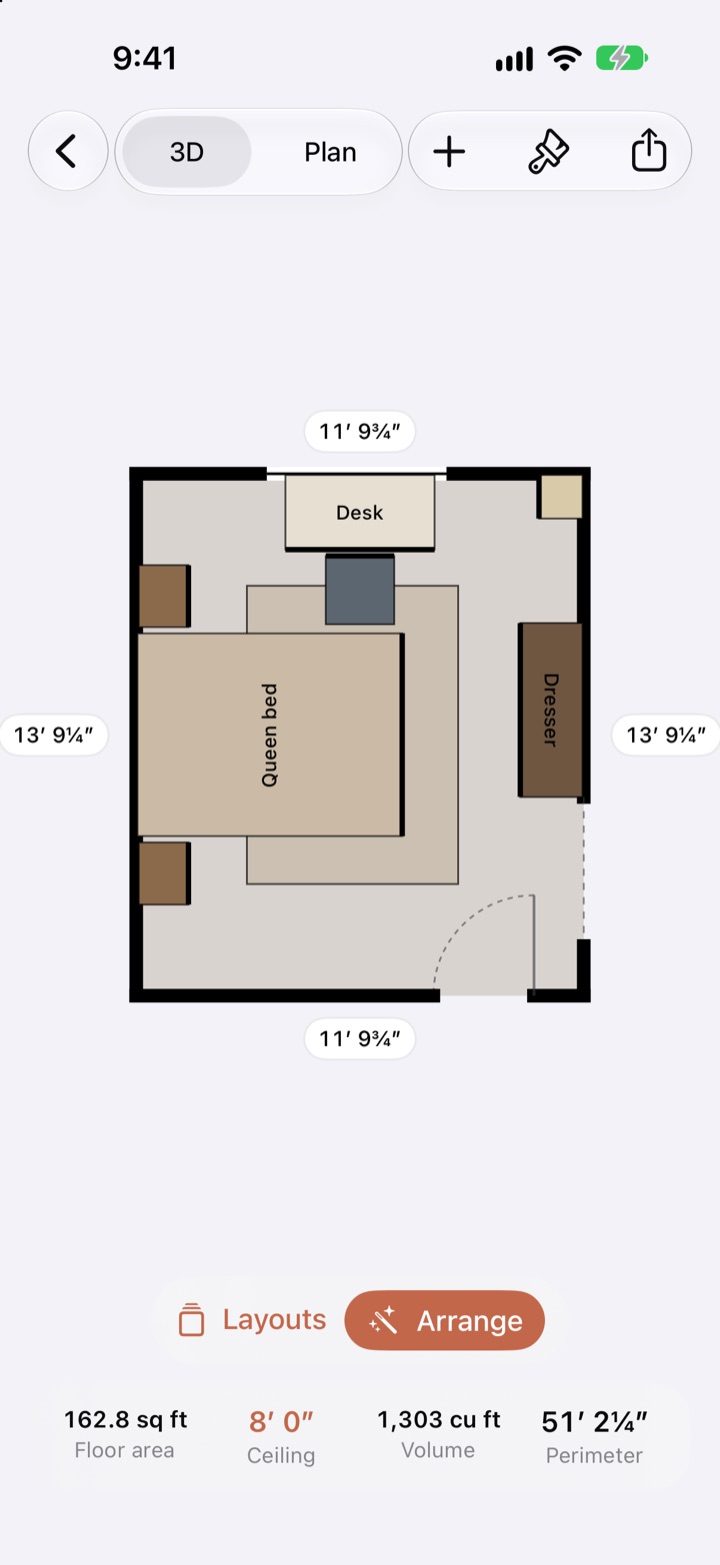 Placed Space on iPhone: a bedroom in plan view, 11 feet 9¾ inches by 13 feet 9¼ inches, with a queen bed between two nightstands, a rug under the bed, a desk under the window with its chair, a dresser, a floor lamp, the door's swing, Layouts and Arrange buttons, and the floor area, ceiling height, volume and perimeter along the bottom.